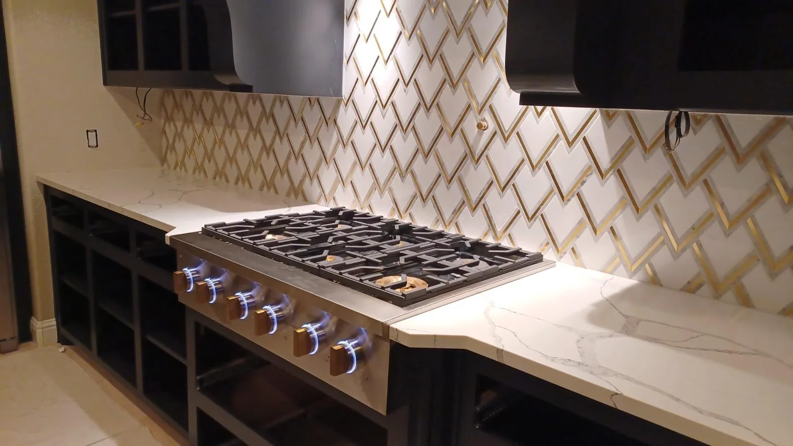 Gold chevron tile backsplash behind a kitchen cooktop