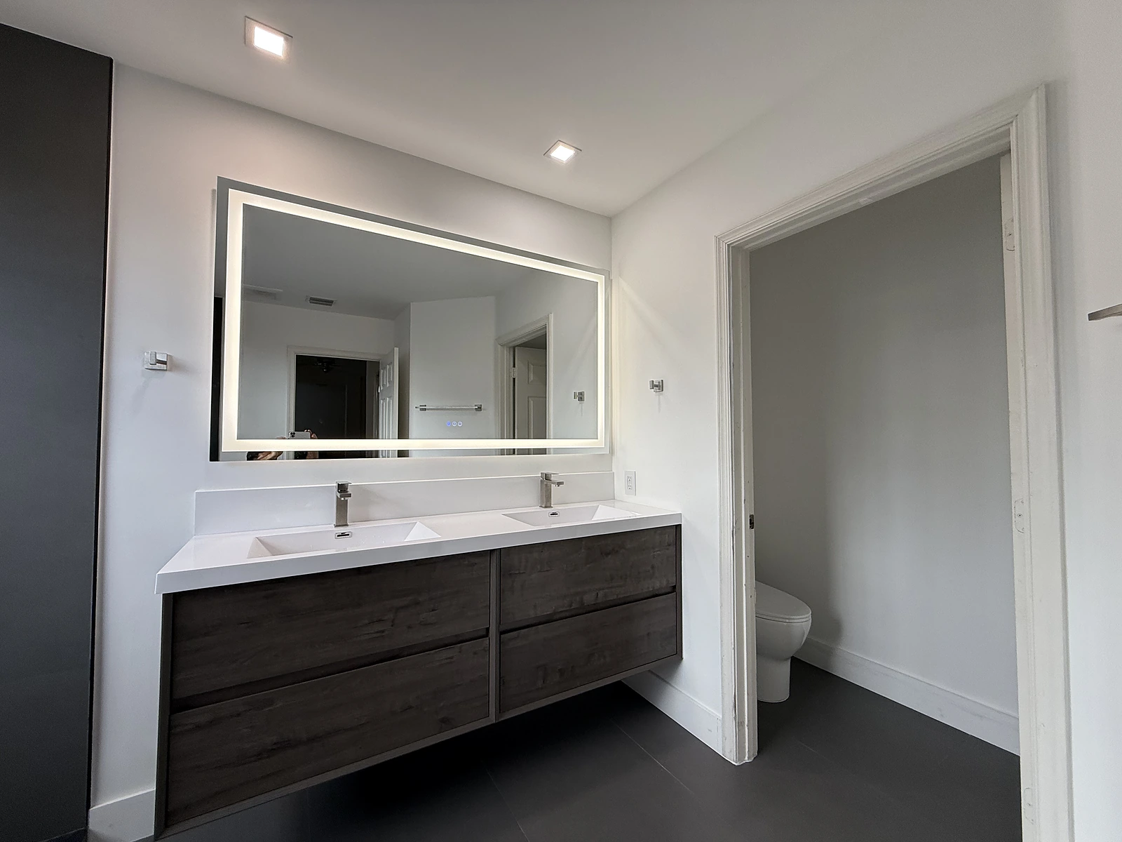 Wood double vanity with backlit mirror in a modern bathroom remodel — West Palm Beach, FL