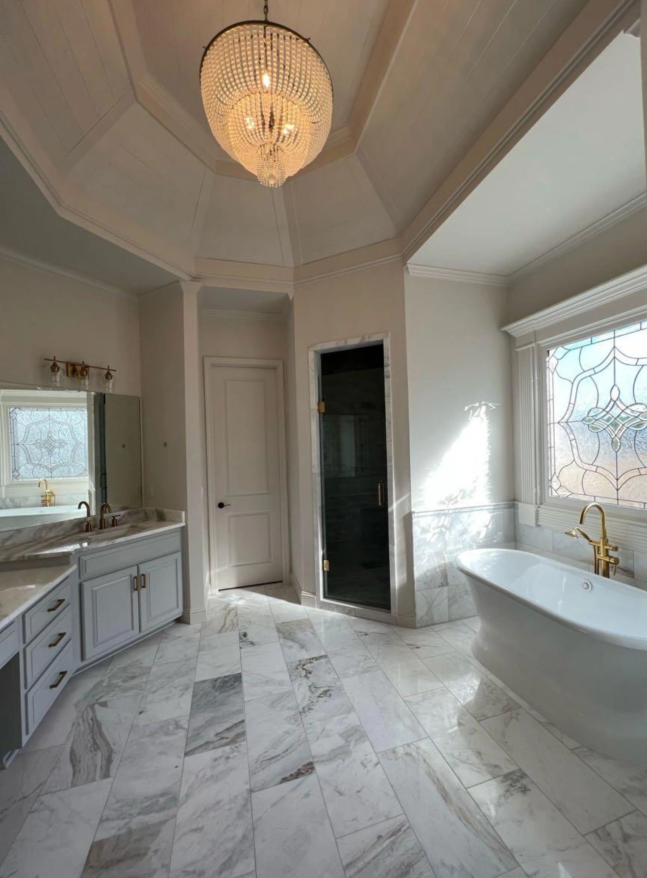Freestanding tub on marble flooring beneath a chandelier — Coral Springs, FL