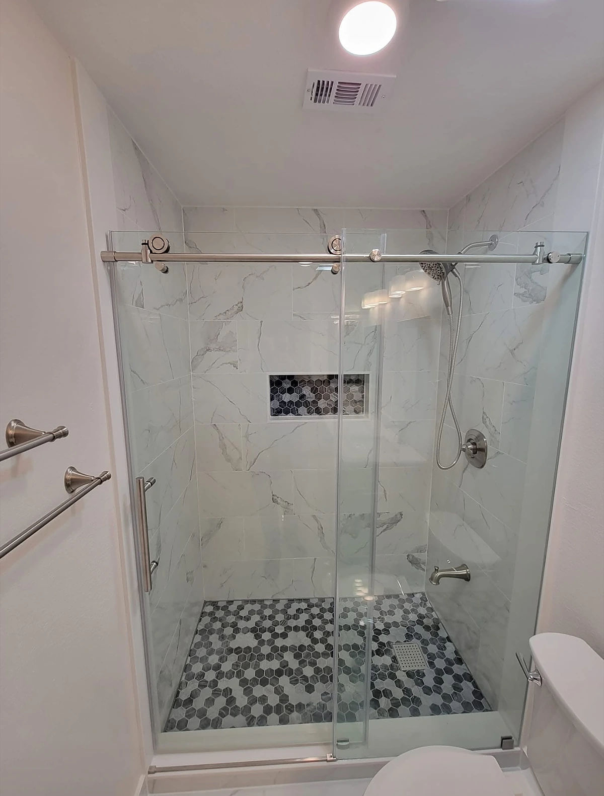 Glass shower enclosure with pebble stone pan and marble walls