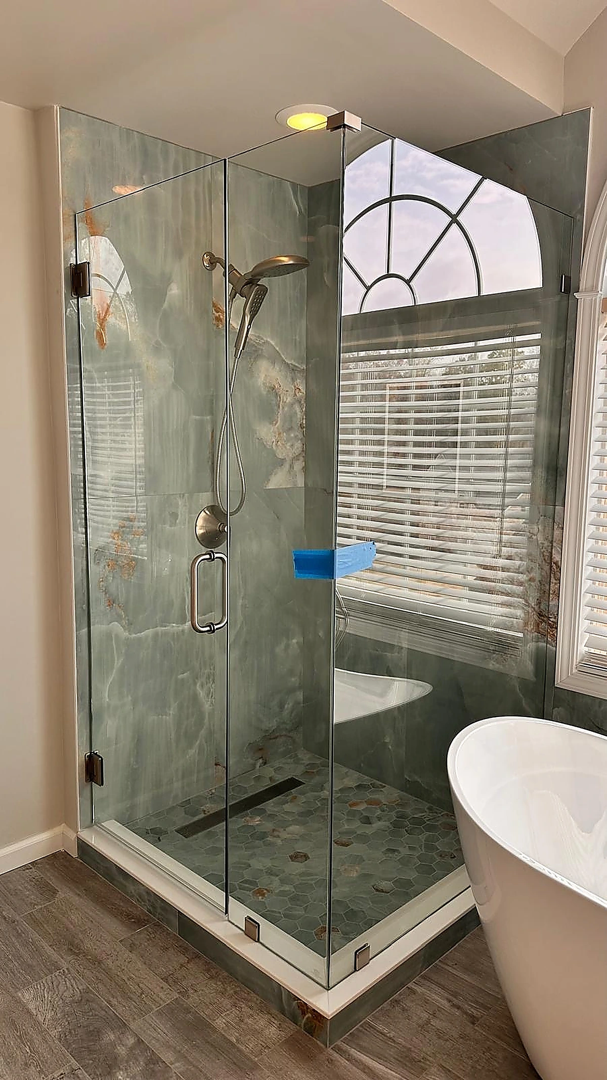 Green-veined marble shower beside a freestanding tub