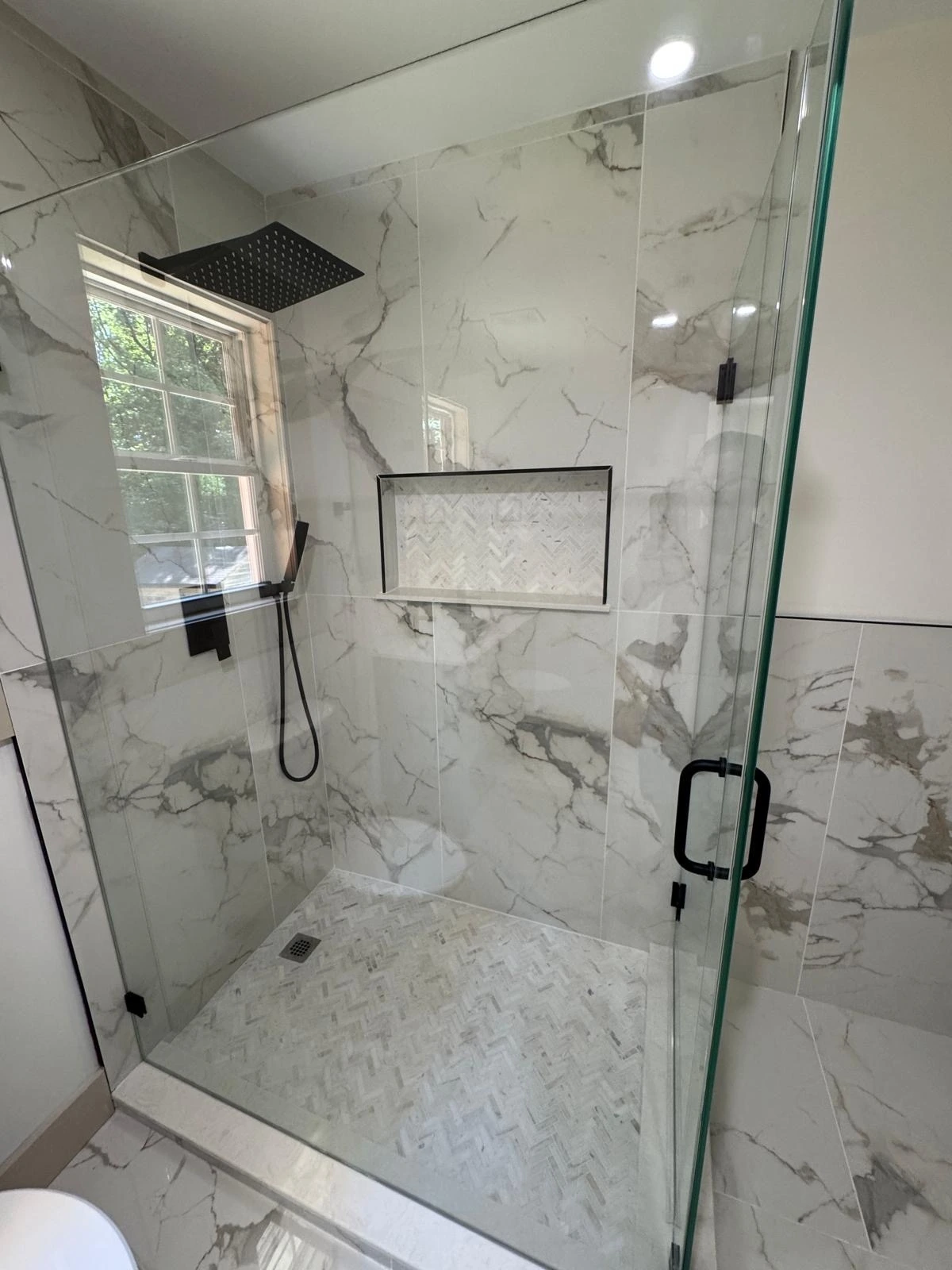 Marble walk-in shower with matte black fixtures and built-in niche — Davie, FL