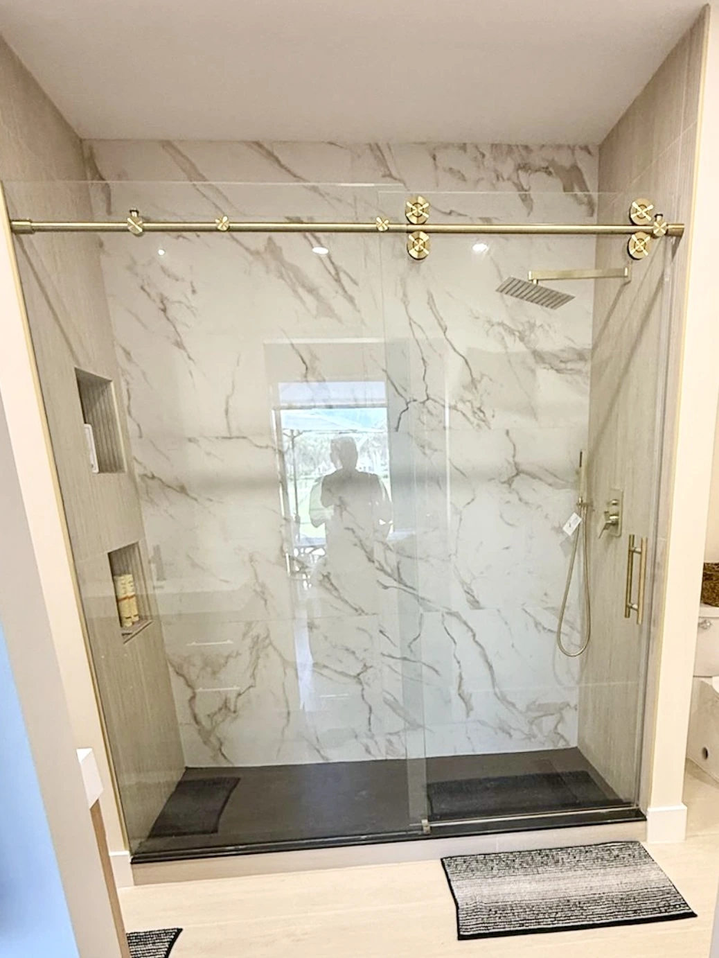 Marble shower with brass hardware and frameless glass panel — Miami, FL