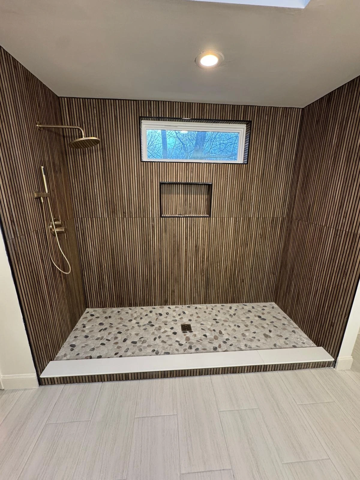 Wide ribbed wood-look tile shower with pebble stone floor — Pembroke Pines, FL