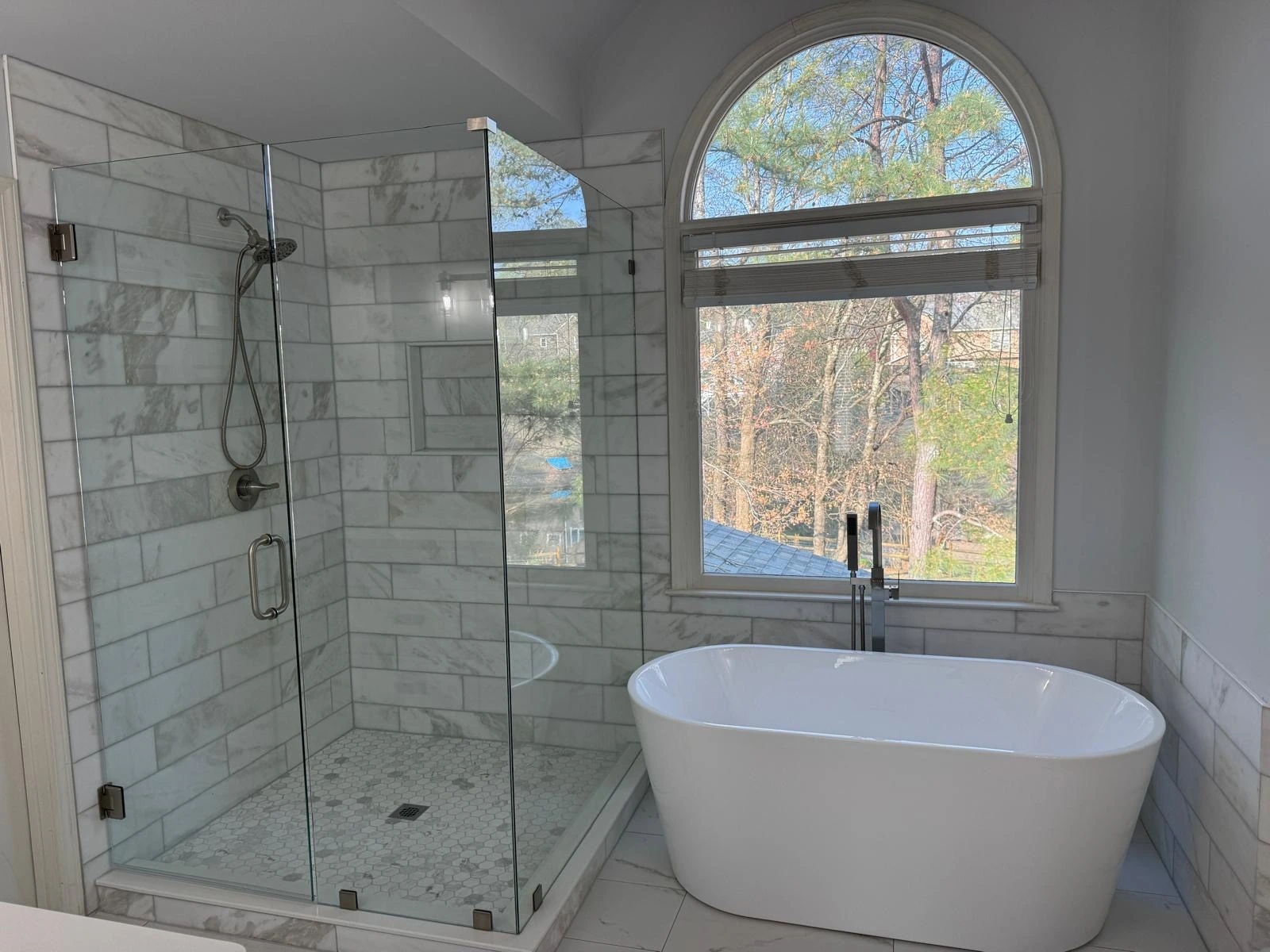 Subway tile shower and freestanding tub beneath an arched window — Pembroke Pines, FL