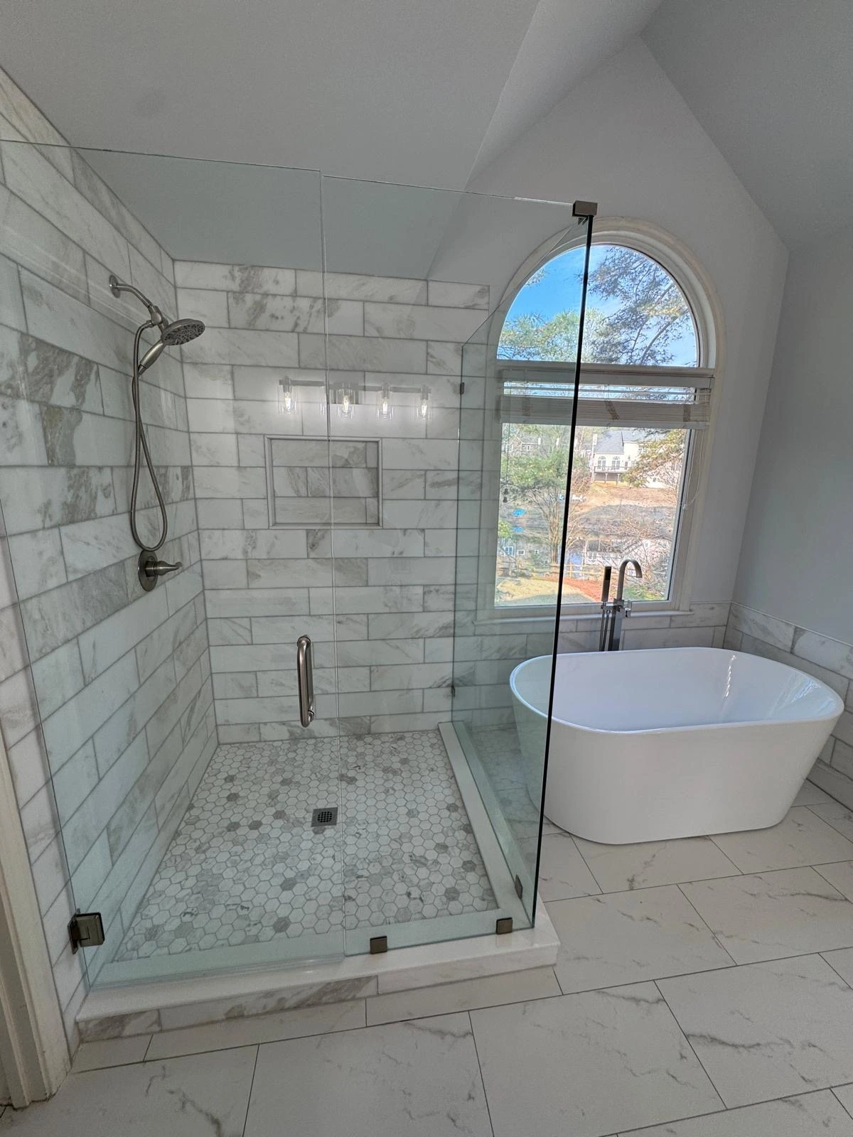 Glass shower and freestanding tub under an arched window — Davie, FL