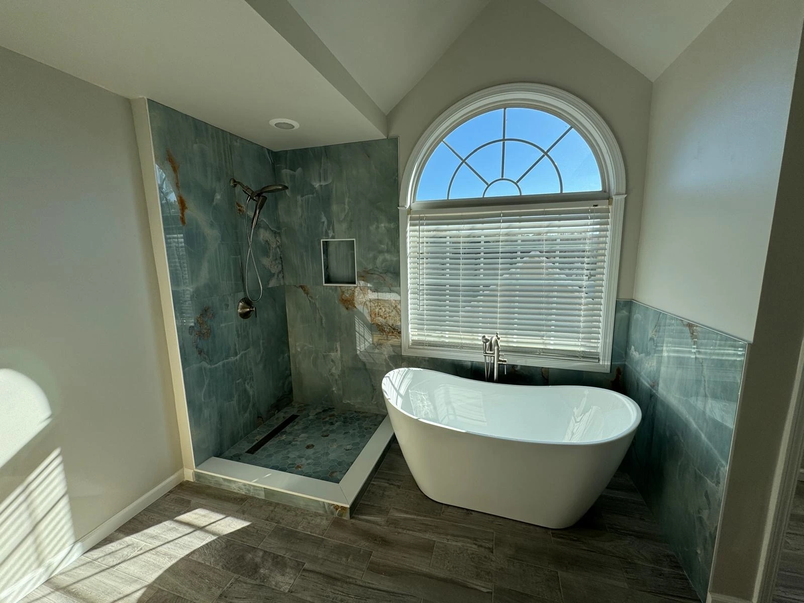 Freestanding tub and green tile shower under an arched window — Aventura, FL