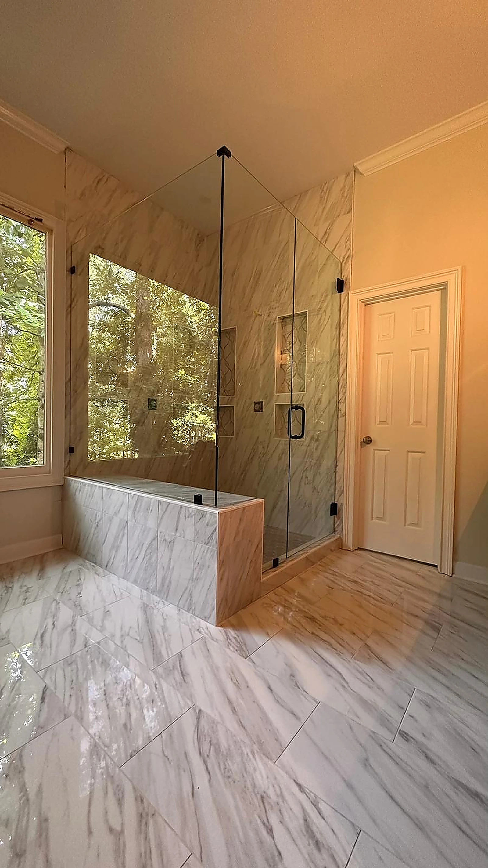 Marble bathroom with soaking tub and glass shower beside a window — Davie, FL