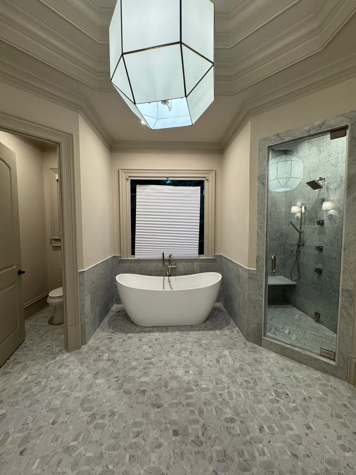 Soaking tub and shower with pebble flooring under a pendant light — Aventura, FL