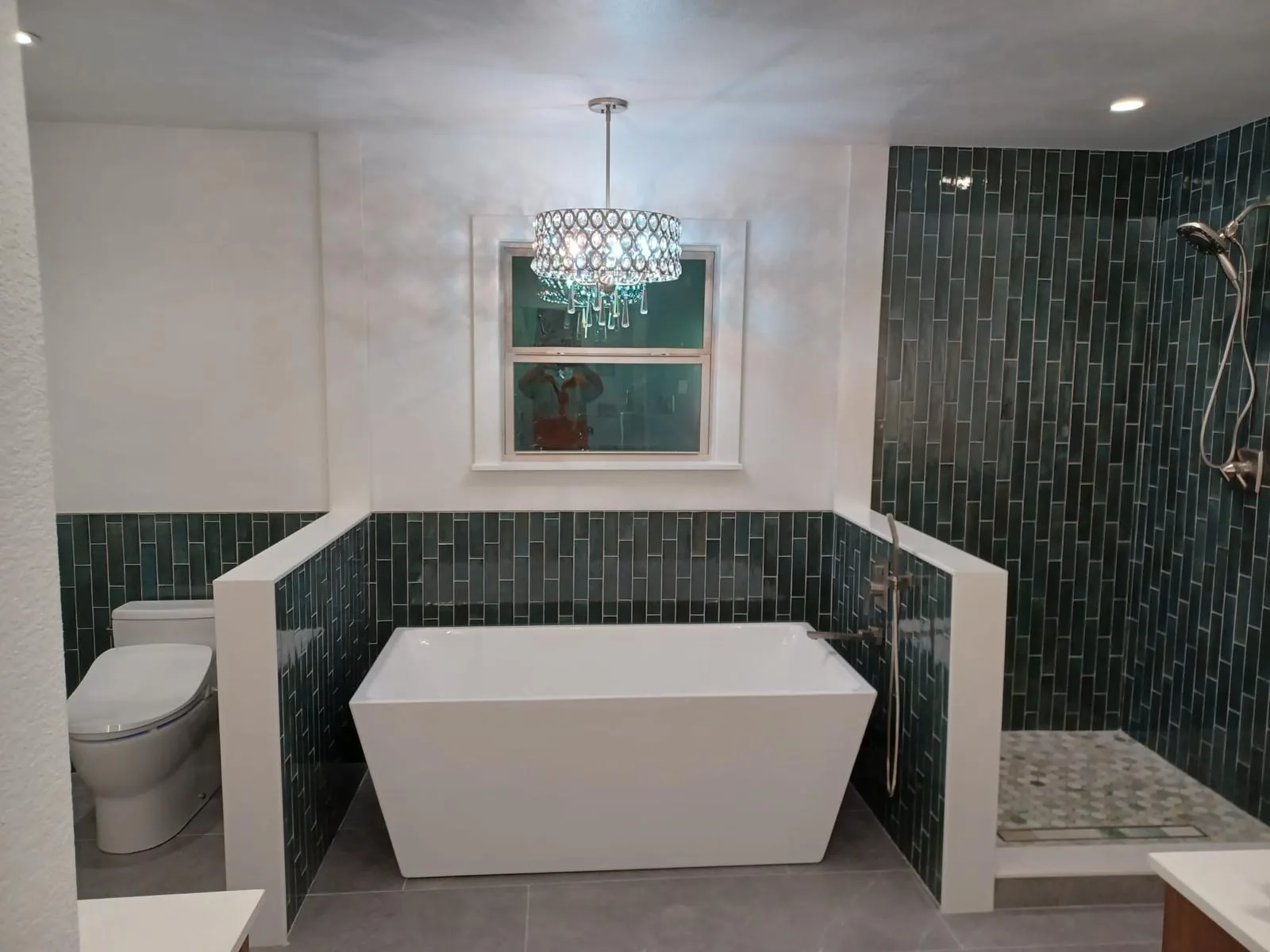 Bathroom with freestanding tub, green tile shower and crystal pendant light — Pompano Beach, FL