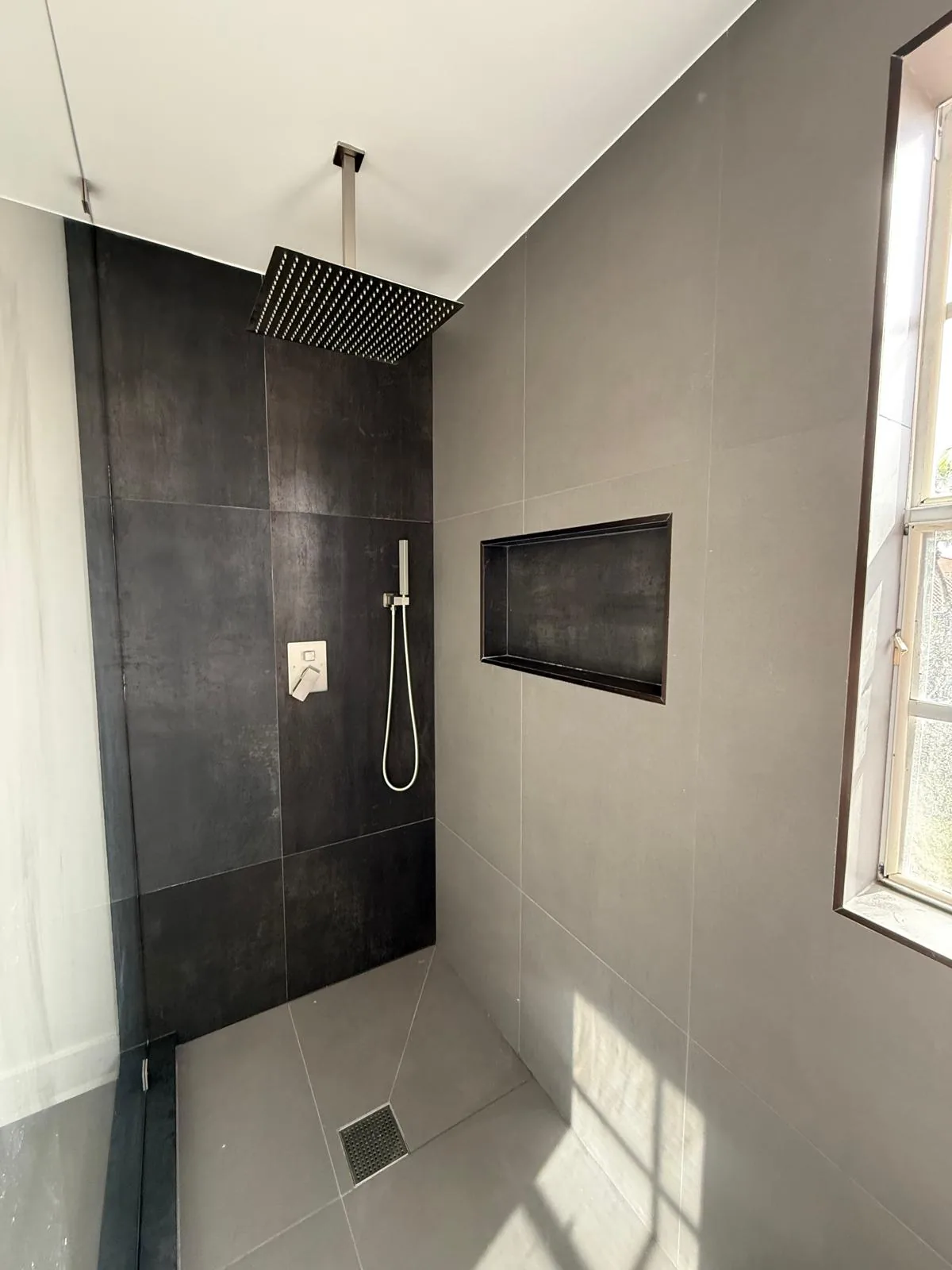 Charcoal tile shower with rainfall head and frameless glass — Fort Lauderdale, FL