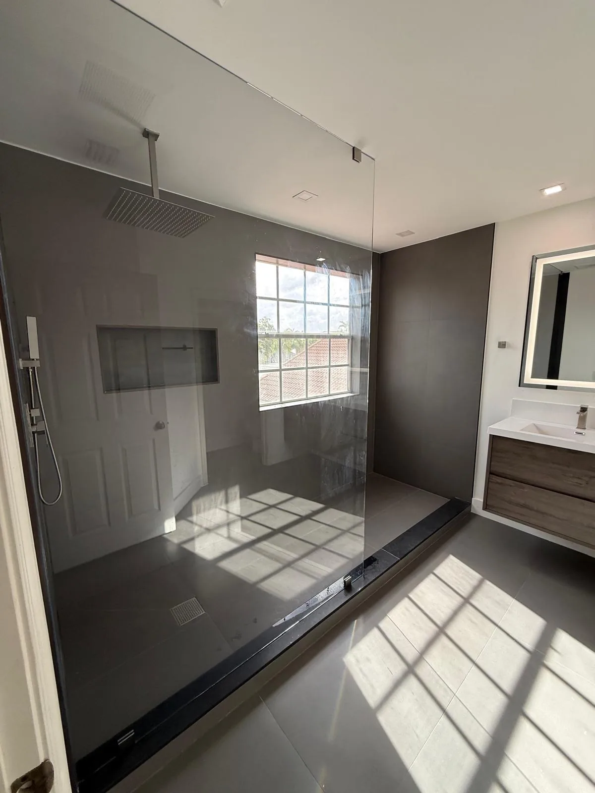 Wide bathroom with dark accent wall, glass shower and floating vanity — Fort Lauderdale, FL
