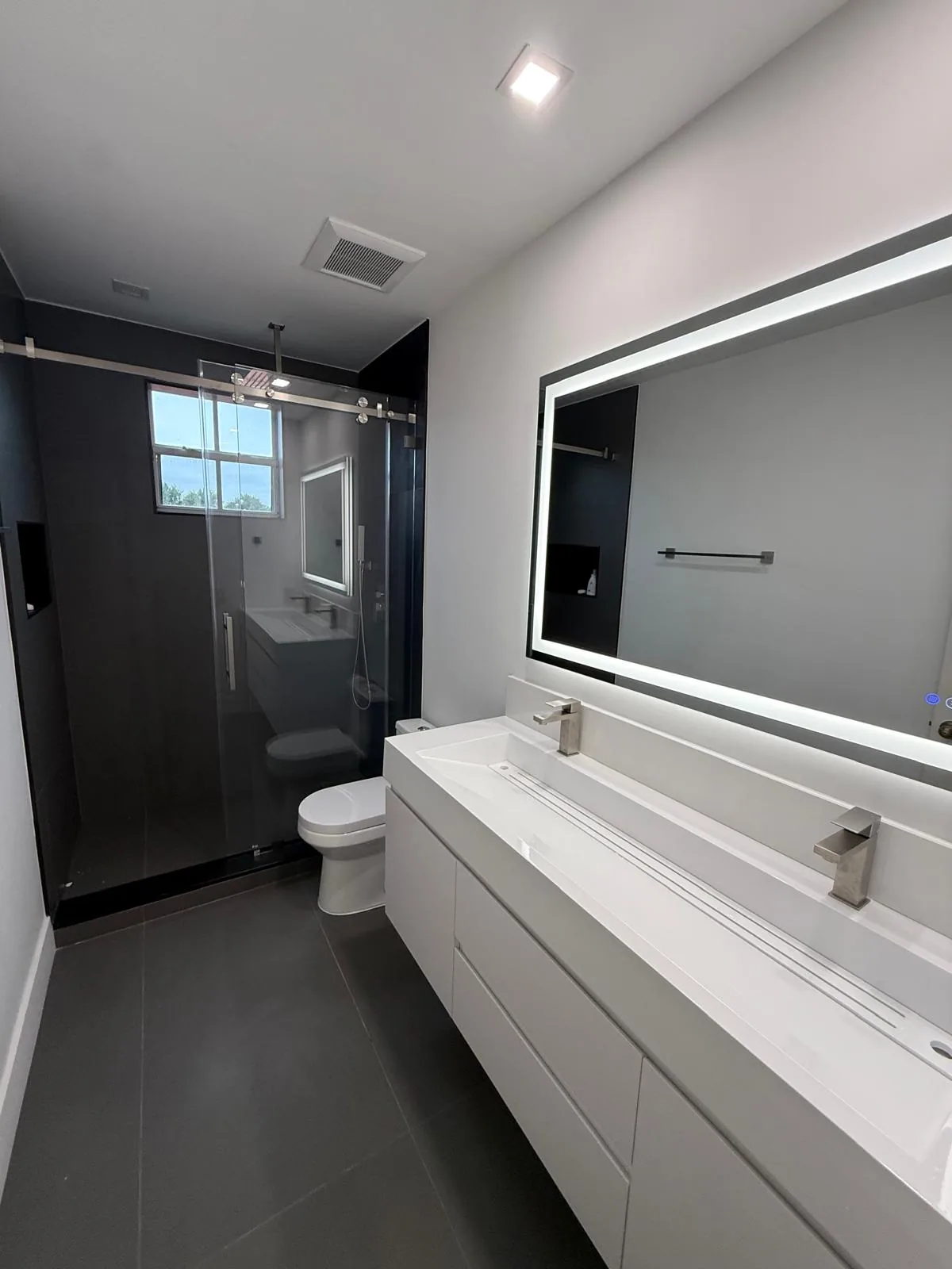 Bathroom with sliding glass shower door and backlit LED mirror — Miami, FL