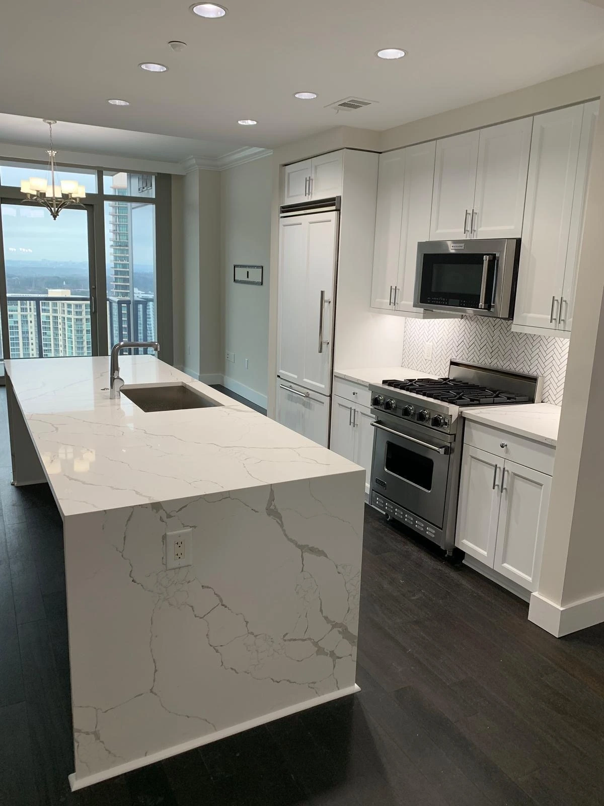 Modern kitchen with a Calacatta quartz waterfall island and a professional gas range