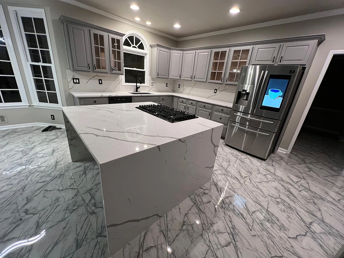 White kitchen with a marble-look waterfall island and glass-front upper cabinets under an arched window