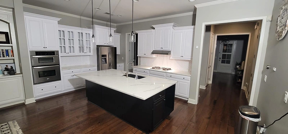 Kitchen with white cabinets, a navy island and a white quartz waterfall countertop