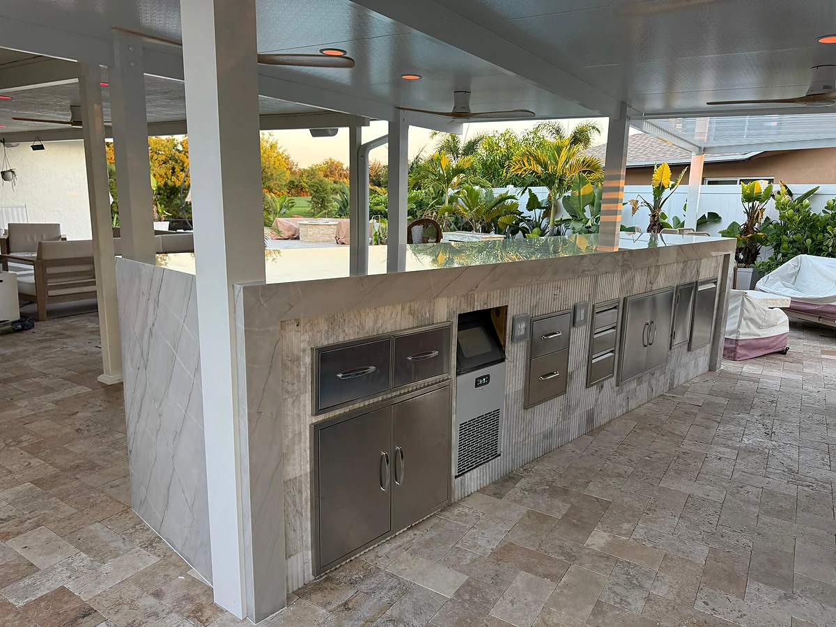 Backyard outdoor kitchen island with a built-in stainless grill, ice maker and marble countertop