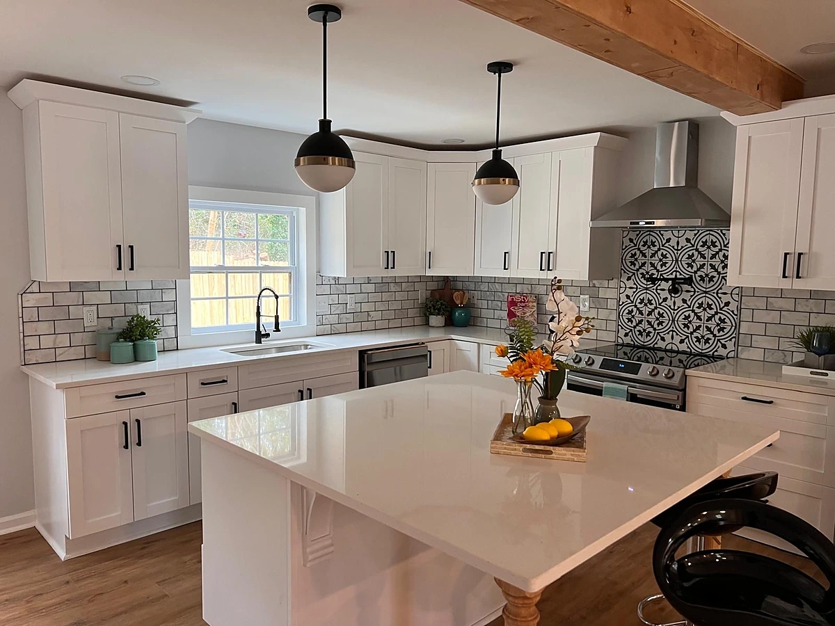 White kitchen with a patterned encaustic and subway tile backsplash and quartz island seating