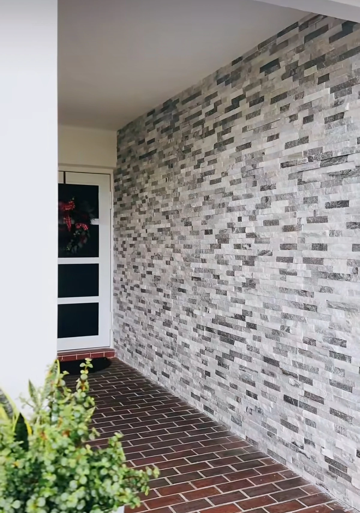 Stacked-stone veneer accent wall at a home entry with a tiled walkway