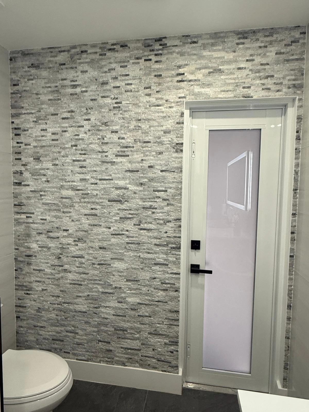 Gray stacked-stone ledger accent wall beside a glass entry door